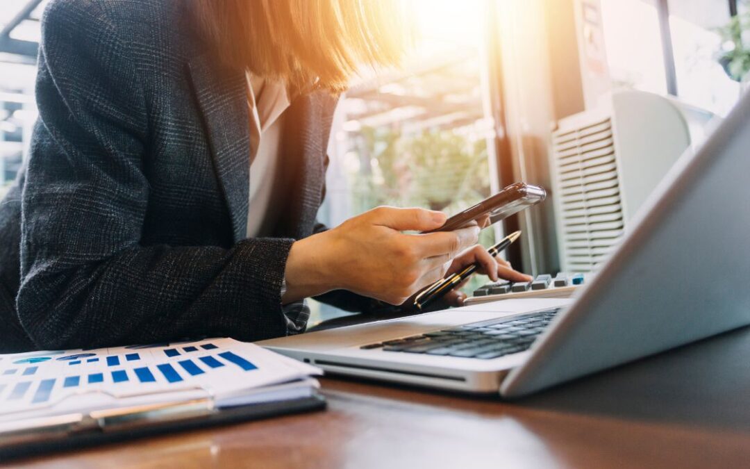 Canva-Zen 9 Marketing Professional SEO Directories woman working at her computer to help improve SEO rankings while holding her cell phone