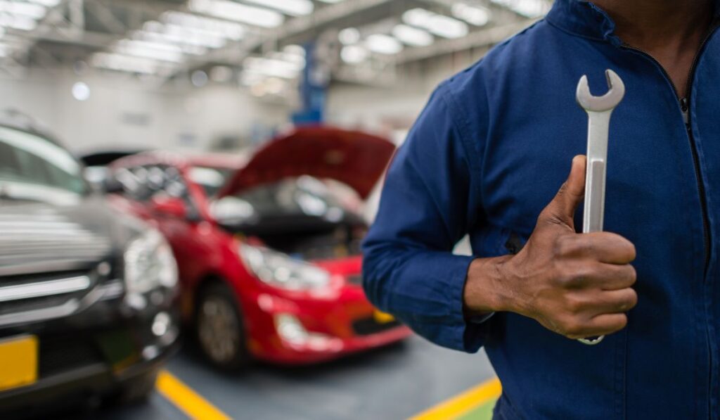 Canva-Zen 9 Marketing auto repair shop SEO mechanic holding a wrench in front of two broken vehicles