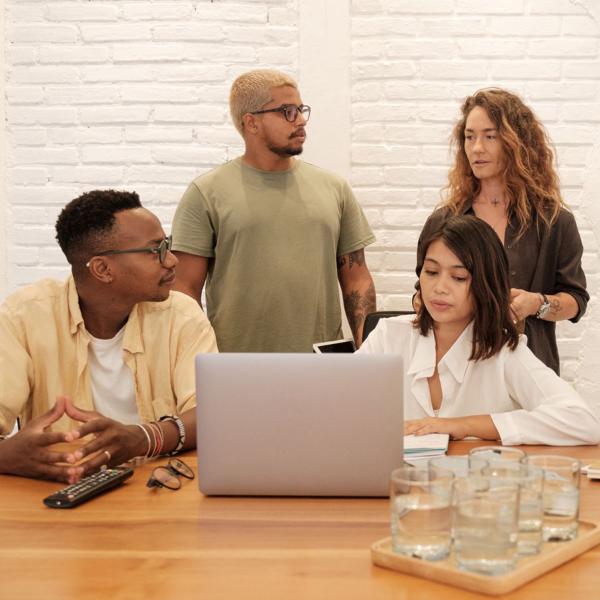 Canva-Zen 9 Marketing Square Four people in an office discussing a client on the laptop in front of them all