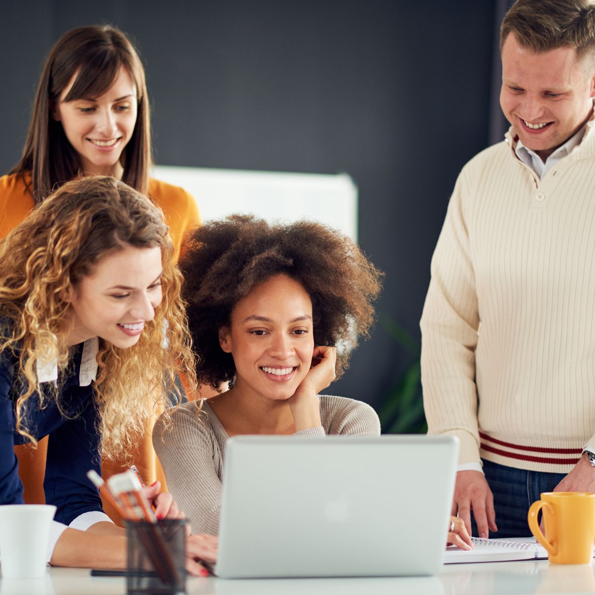 Canva-Zen 9 Marketing Square Four people in an office looking at a laptop and smiling over successful campaign results