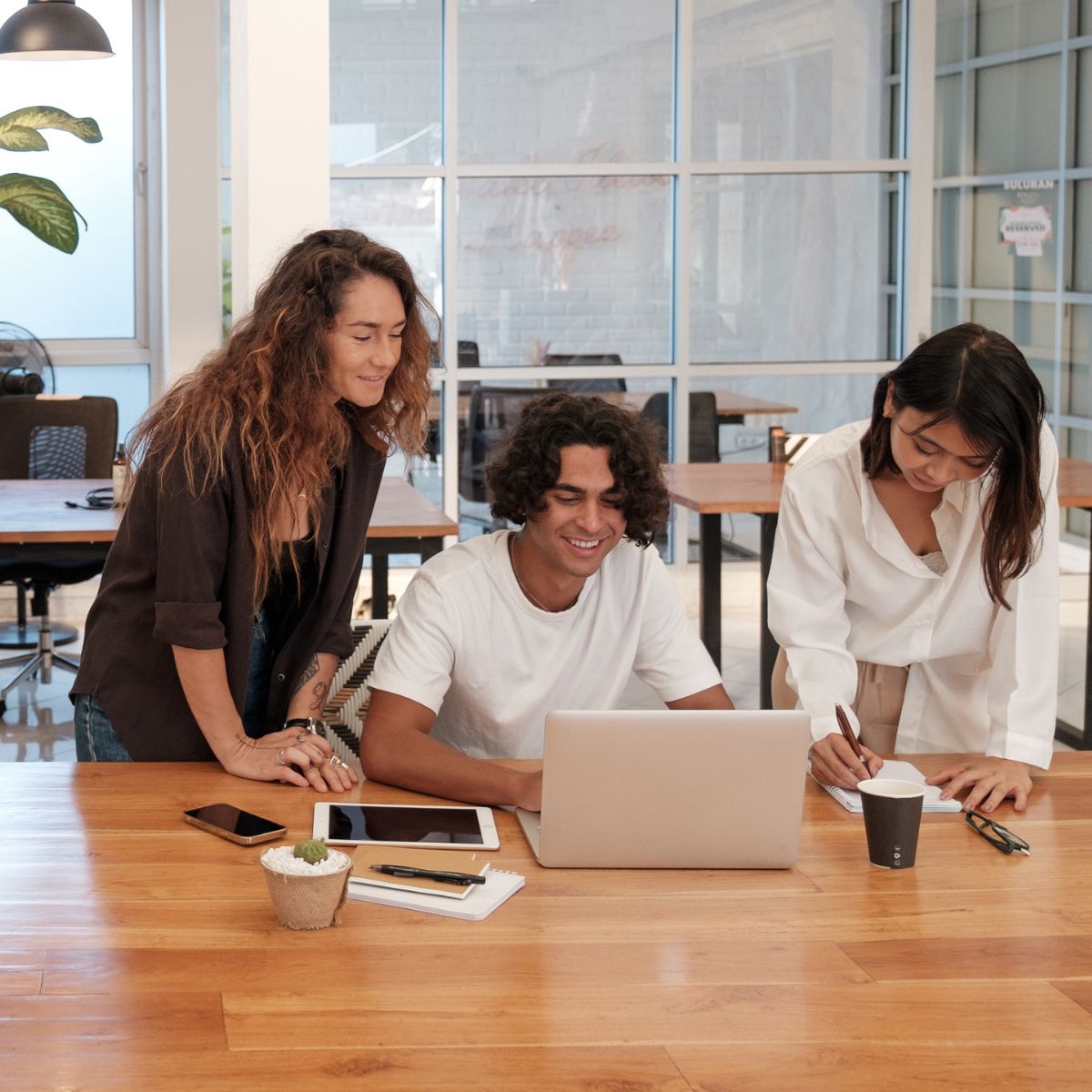 Canva-Zen 9 Marketing Square Three people in an office working over a laptop together taking care of their clients