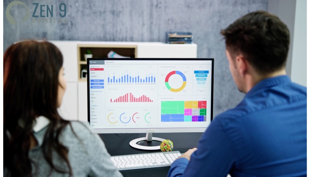 2 business people sitting in front of a computer going over website performance statistics